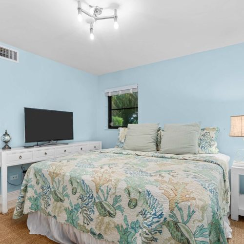 Bright king bedroom with a coastal vibe and a tv for easy wind-down at night.