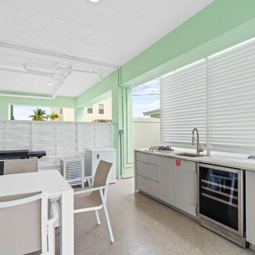 Outdoor kitchen with beverage cooler and sink makes entertaining a breeze, just steps from the pool and grill for seamless outdoor living.