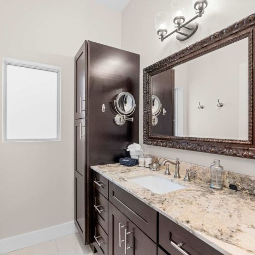 Primary bath: granite vanity, framed mirror, and a lighted makeup mirror to get ready.
