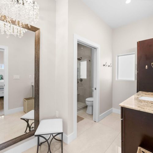 Primary bath: a spa-style vanity area with a floor mirror and walk-in shower beyond.