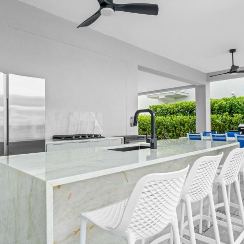 Spacious outdoor kitchen with bar seating overlooking the pool.