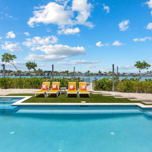 Loungers line the turf sun pad between the heated pool, built-in spa, and harbor views.