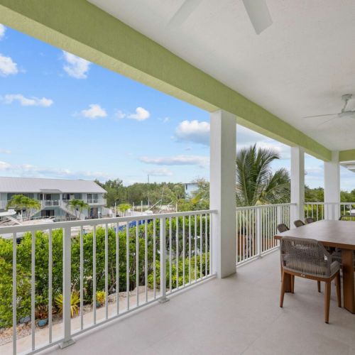Covered balcony: dine alfresco above the pool with the canal and boats just beyond the rail.