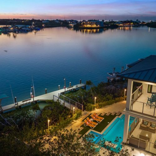 Balconies cascade to the illuminated pool deck and dock reaching into the harbor.
