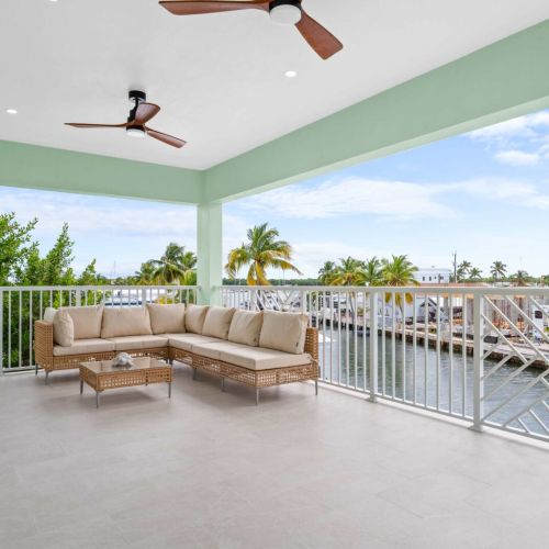 Expansive covered balcony with plush seating and stunning canal views, ideal for morning coffee or sunset cocktails with your crew,