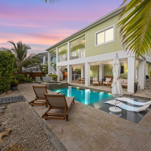 Waterfront pool & spa: pink keys skies, a glowing pool, and loungers steps from the patio.