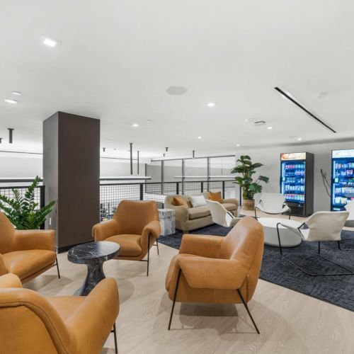 Mezzanine lounge: leather club chairs, marble side tables, and stocked vending machines turn the upper level into a low-key hangout between meetings or workouts.