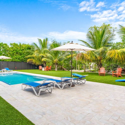 The pool sparkles under the sun, framed by palms and bright loungers that call for slow mornings and long afternoons. Play cornhole, dip into the water, or unwind by the firepit while the keys breeze drifts through.