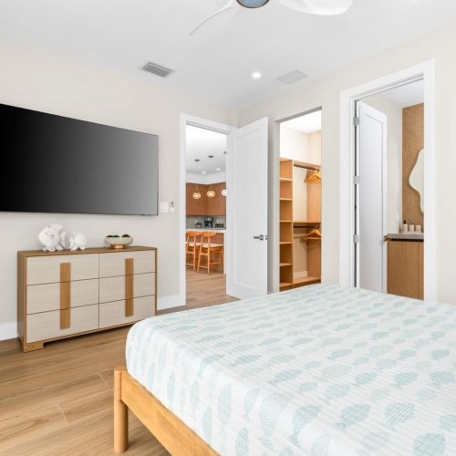 Spacious master bedroom with large smart tv and open flow to the kitchen, perfect for relaxing mornings with coffee in bed.