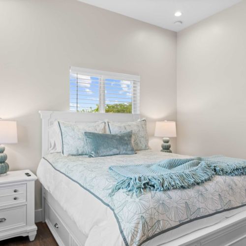 Guest bedroom: a calm sand-and-sea palette with a queen bed and bedside lamps.