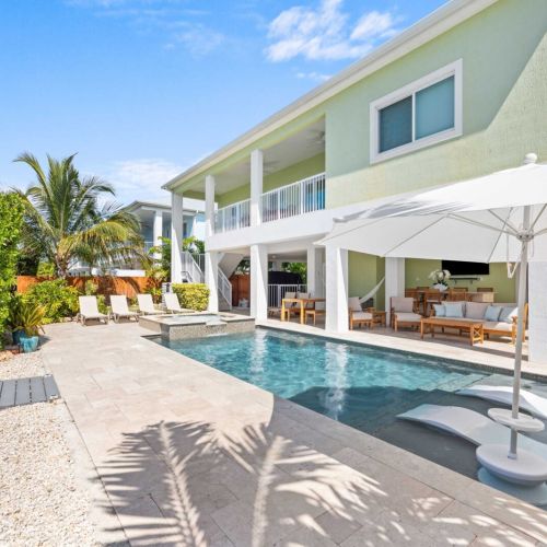 Waterfront pool & spa: blue keys skies, a glowing pool, and loungers steps from the patio.
