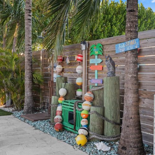 Escape to a charming getaway where nature meets comfort! Picture this: a quaint wooden fence, a cozy sign welcoming you home, and a tree complete with a birdhouse just outside your door.