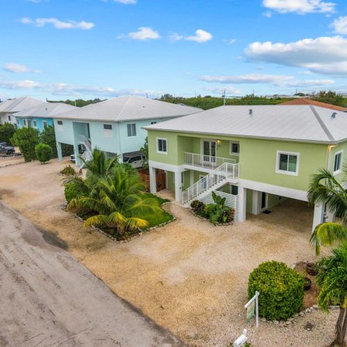 Street view: a bright keys retreat with palm-lined gravel drive and covered parking.