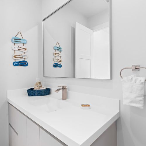 Step into luxury with this exquisite bathroom setup featuring a sleek sink, a stylish mirror, and a convenient towel rack.