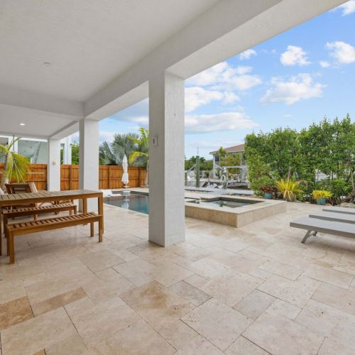 Pool patio: wide travertine decking with a hammock, loungers, and the pool at center.