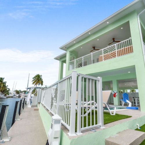 Modern two-story waterfront retreat with multiple outdoor living spaces, private dock, and direct ocean access for the ultimate keys vacation experience.