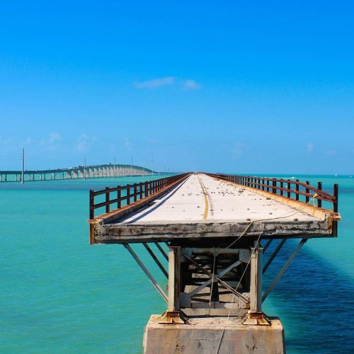 Experience the breathtaking beauty of the ocean as you stroll across this magnificent bridge. With a stunning blue sky above, this location is perfect for creating unforgettable memories.