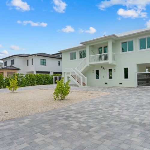 The perfect blend of elegance and nature - a house with a grand brick driveway and serene trees in the backdrop