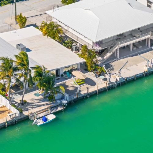 Discover your next getaway with this stunning aerial view of our charming resort! Dive into relaxation by the swimming pool surrounded by lush palm trees and beautiful scenery. Your perfect outdoor escape awaits!