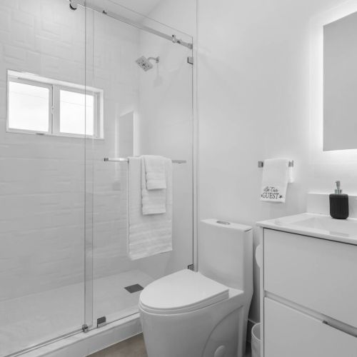 Fresh minimalist bathroom with glass shower and plenty of natural light.