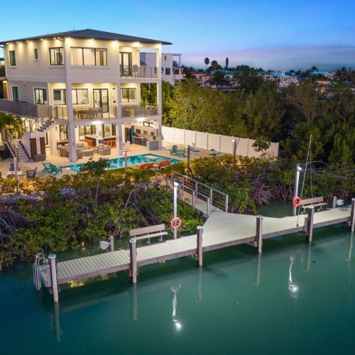 Private dock with boat lift, heated pool, and covered balconies facing the harbor.