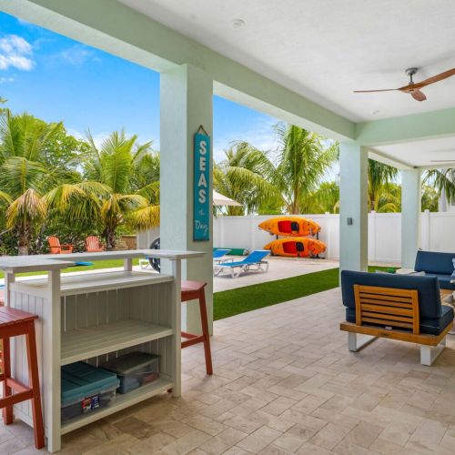 Outdoor living done right. Sip a drink at the bar, relax in the shaded lounge, or step out to the pool framed by palms and sunshine. This space was made for easy days, laughter, and island-style connection.