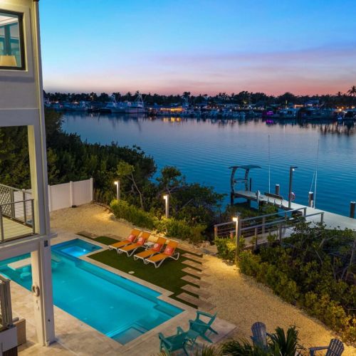 The pool glows as marina lights flicker across the harbor beyond the dock.