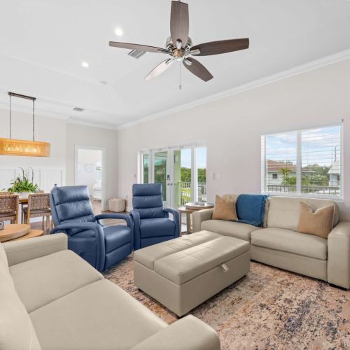 Living room: leather seating under the ceiling fan with water views across the room.