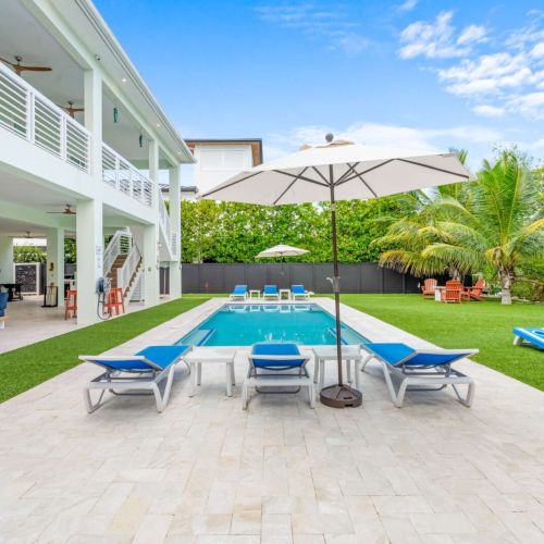 Poolside perfection framed by palms and sunshine. Stretch out on the loungers, take a dip, or enjoy a lazy afternoon under the shade of an umbrella. Every inch of this backyard is made for effortless relaxation and good company.
