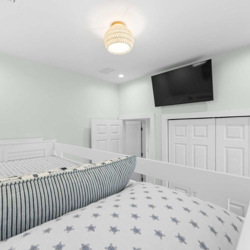 Bunk room: playful turtle bedding and a wall tv for movie nights up top.