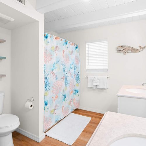 Enjoy a refreshing shower behind the cheerful curtain, and don’t forget to admire the chic tiles and fixtures. Your perfect getaway awaits!