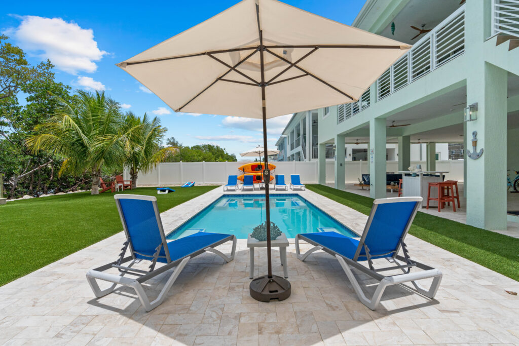 Private swimming pool with lounge chairs and umbrellas at Emerald Oasis in Marathon, Florida, ideal for relaxing and enjoying vacation rentals.