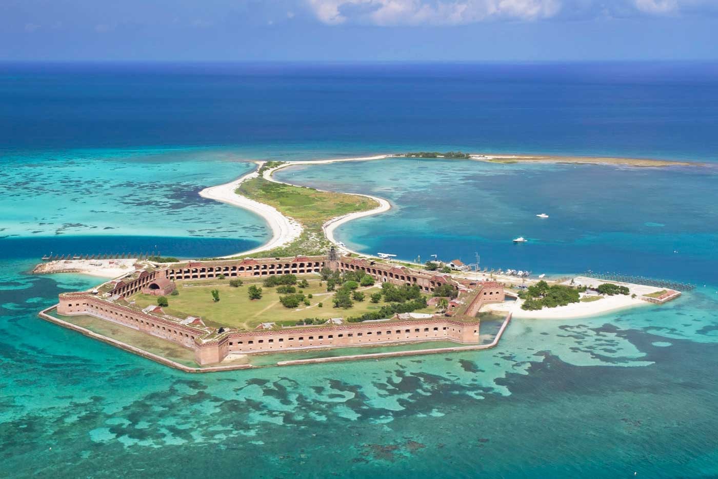 Aerial view of fort jefferson, a large hexagonal brick fortress on a small island surrounded by turquoise water and coral reefs—an iconic spring break in the florida keys destination in the dry tortugas.