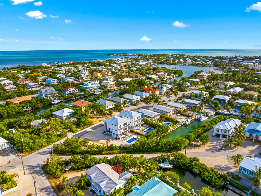 Isla sol: best waterfront vacation rental in marathon fl with pool & dock 13 Aerial view of a coastal neighborhood with houses, pools, and canals surrounded by lush greenery, near a blue ocean under a clear sky.
