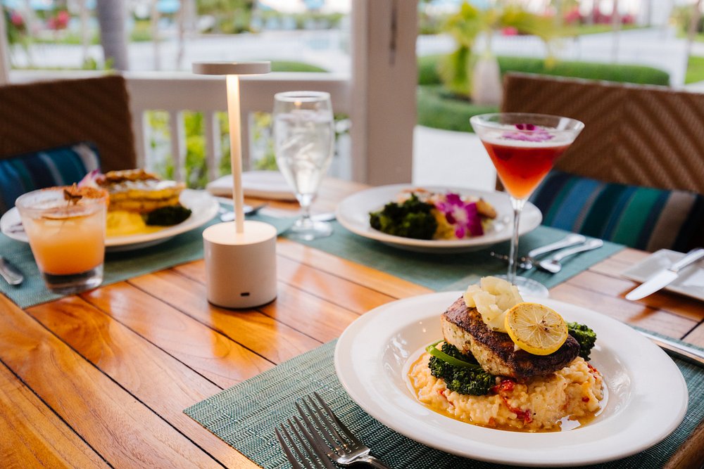 The ultimate marathon fl restaurants scene: from casual to fine dining 8 A plated meal of fish over mashed potatoes with vegetables sits on a set table, alongside drinks and another plate of food, in a bright, outdoor dining setting.