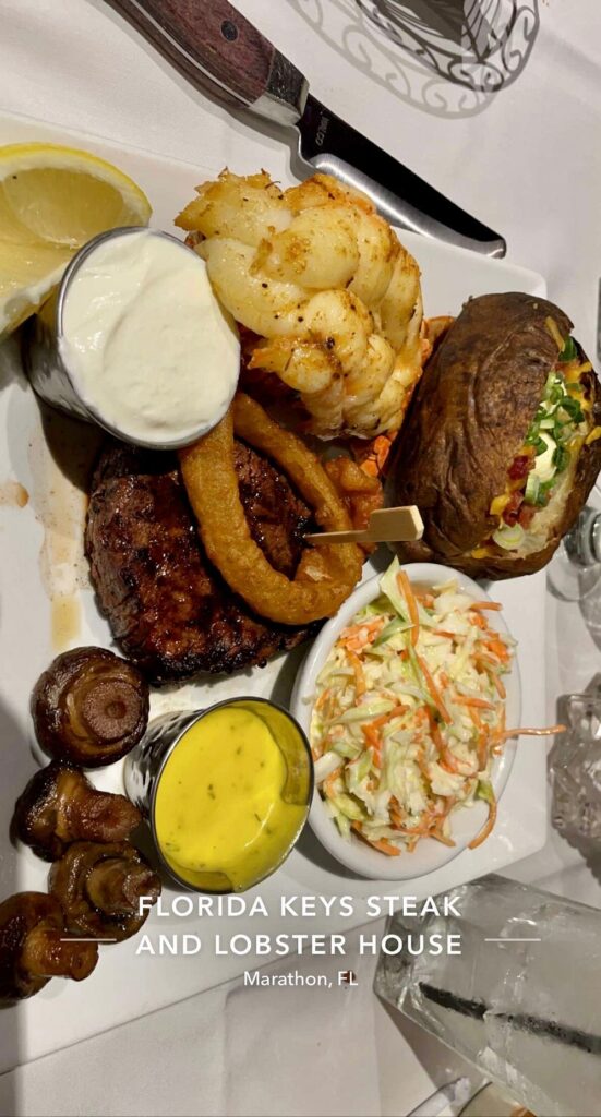 The ultimate marathon fl restaurants scene: from casual to fine dining 10 A dinner plate with grilled steak, lobster tail, baked potato with toppings, coleslaw, sautéed mushrooms, onion rings, lemon wedges, and two dipping sauces, on a white tablecloth at florida keys steak and lobster house.