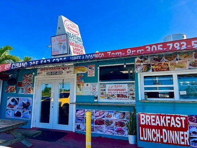 The ultimate marathon fl restaurants scene: from casual to fine dining 14 A vibrant cuban restaurant with turquoise walls, food photos, and signs advertising breakfast, lunch, and dinner. A picnic table sits outside under a clear blue sky. The restaurant’s windows display menus and red lettering.