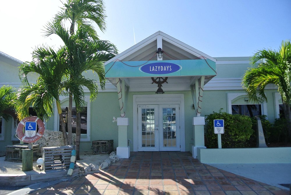 The ultimate marathon fl restaurants scene: from casual to fine dining 11 Entrance of a light green building with palm trees, a sign reading lazydays, and two wheelchair accessible signs near the door. The sky is clear and sunny.
